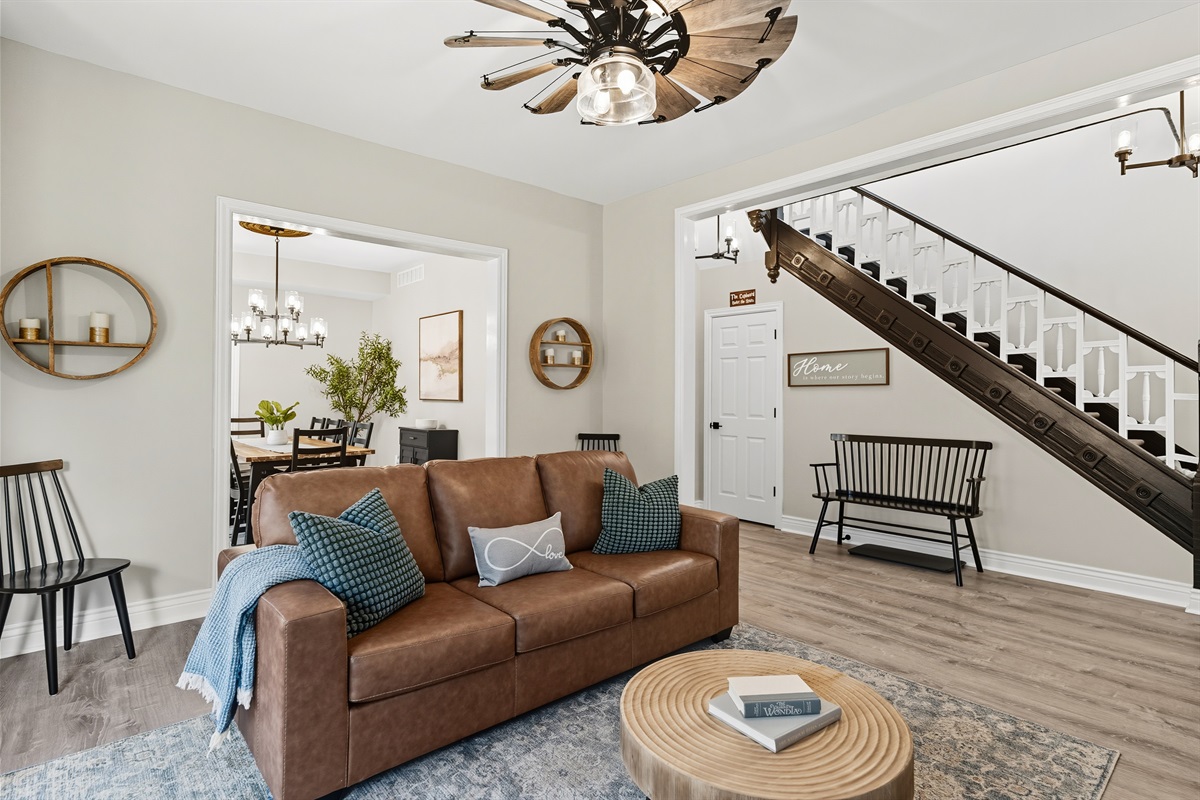 Living room with brown leather sofa and windmill ceiling fan
